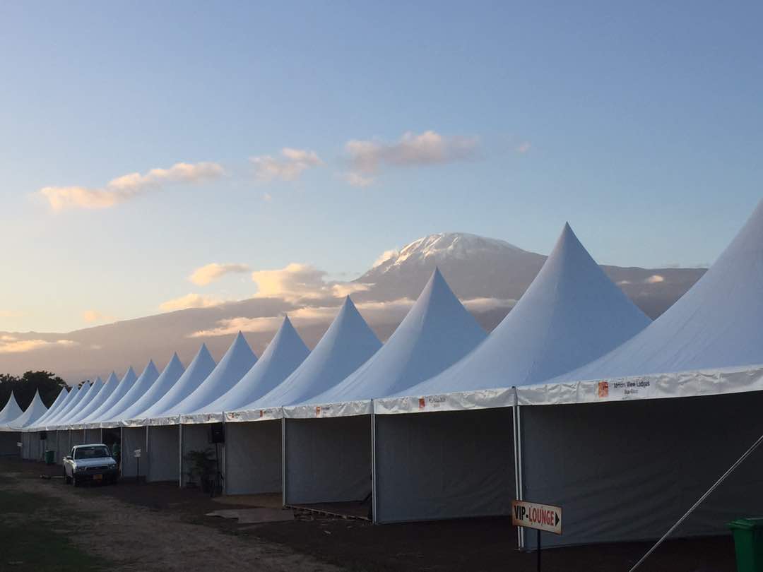 Long row of linked white pagoda tents forming an exhibition village at sunset