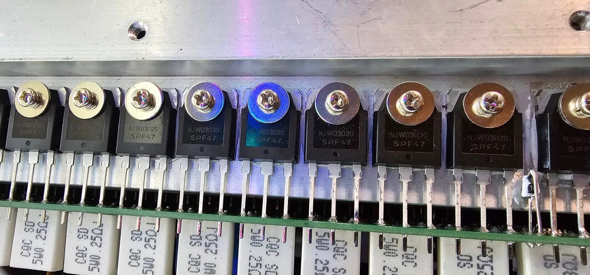 Row of NJW0302G power transistors bolted to an aluminium heatsink on an amplifier output stage