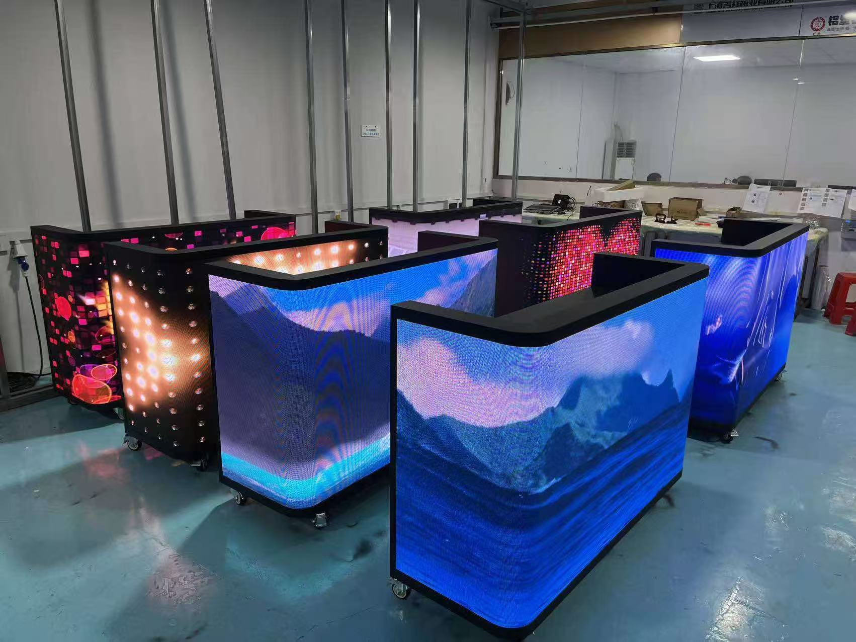 LED DJ booths with curved corners showing blue mountain video content