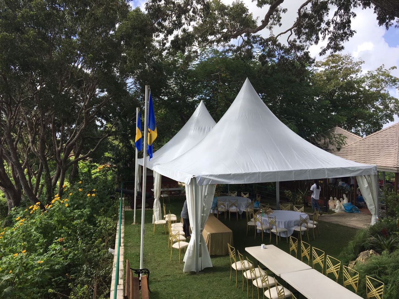 Two white pagoda tents joined together over a garden wedding reception with round tables